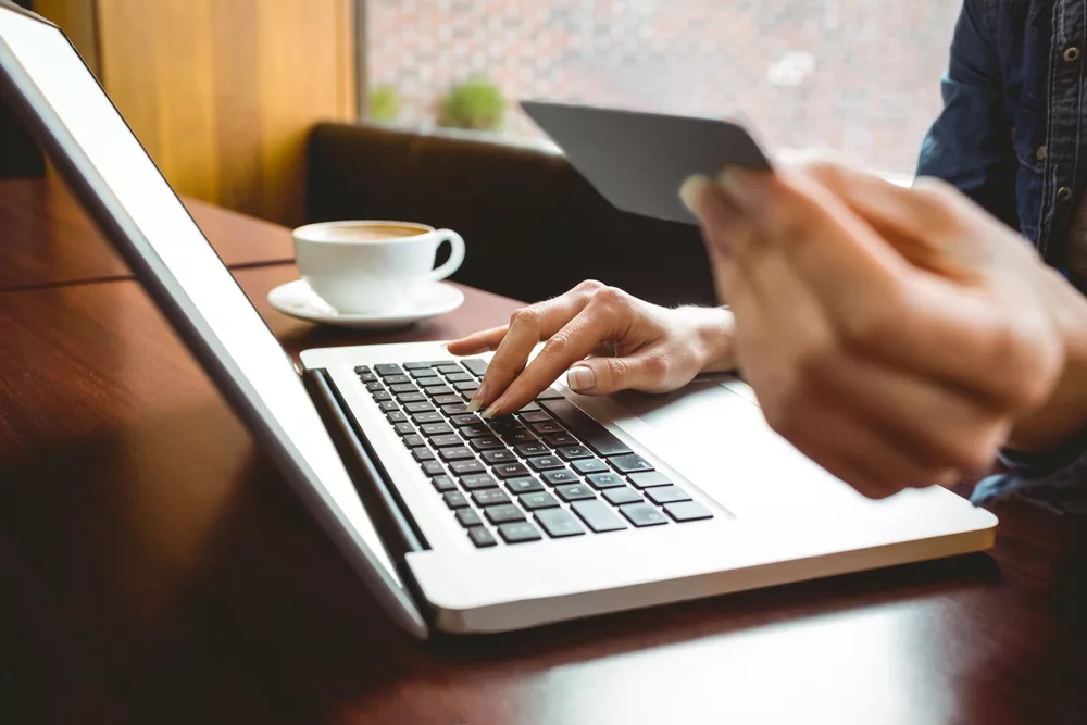 Étudiant utilisant un ordinateur portable dans un café pour faire des achats en ligne